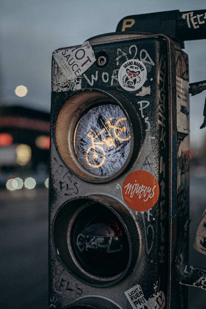 Traffic light covered in street art stickers creating an urban grunge aesthetic.
